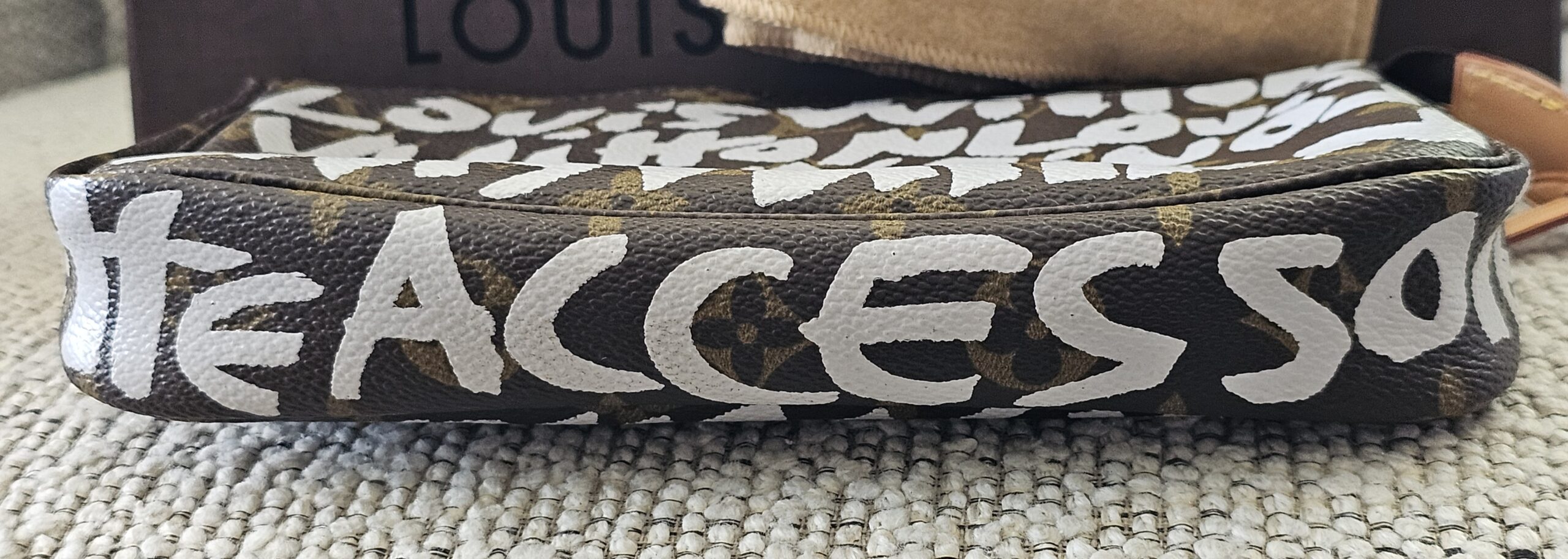 Top of the Louis Vuitton Graffiti Pochette Accessoires showing the graffiti lettering along the zip
