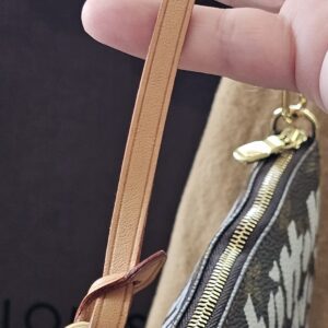 Natural vachetta leather wrist strap of the Louis Vuitton Graffiti Pochette Accessoires, showing almost no patina
