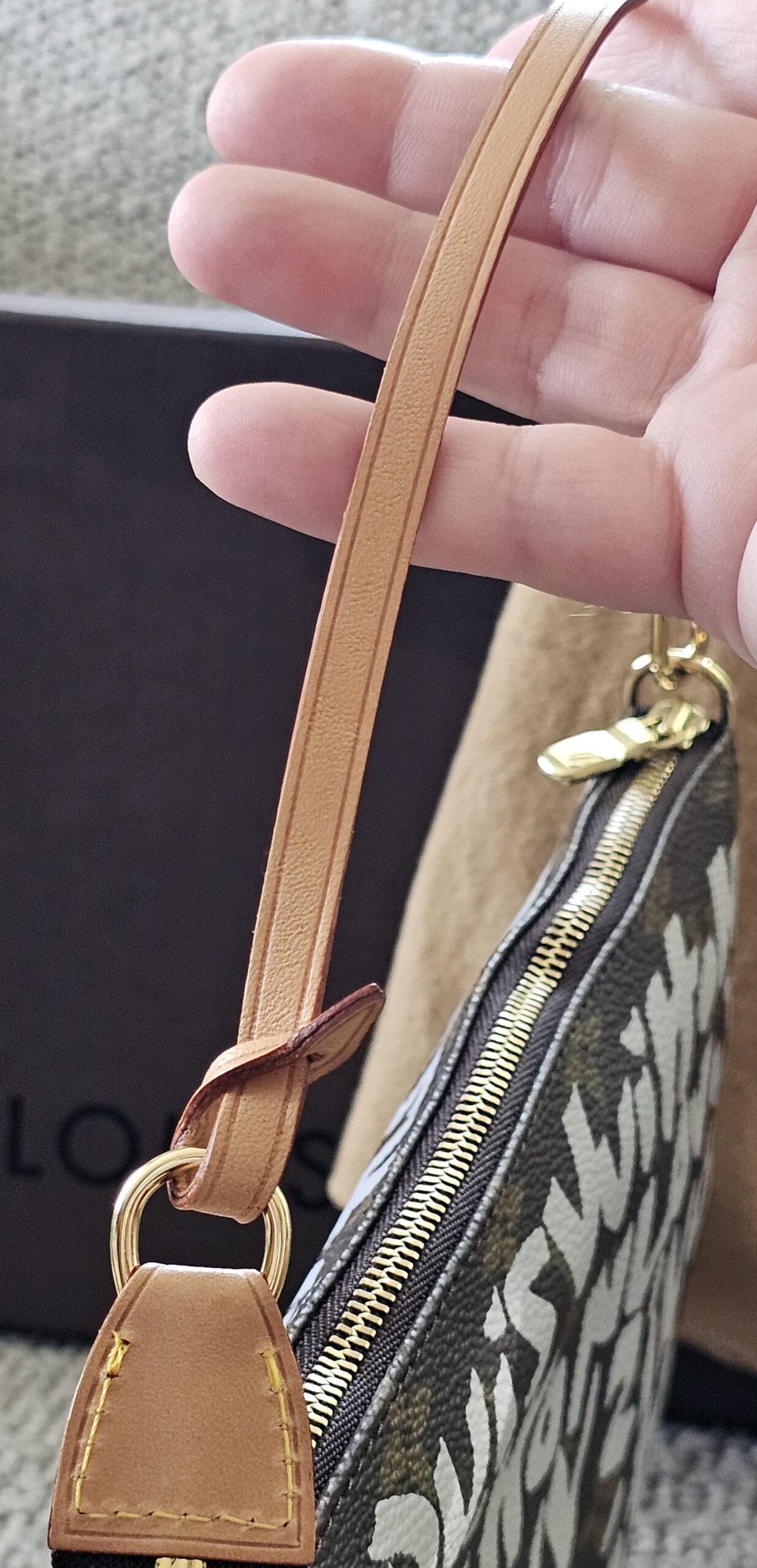Natural vachetta leather wrist strap of the Louis Vuitton Graffiti Pochette Accessoires, showing almost no patina