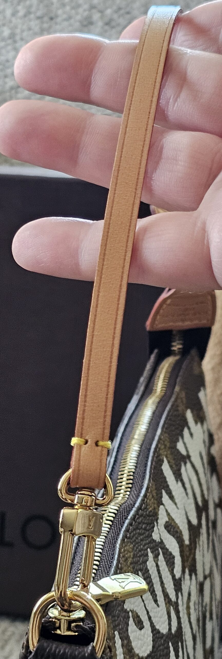 Gold-tone clasp attaching the vachetta wrist strap to the Louis Vuitton Graffiti Pochette Accessoires