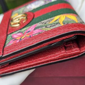 Side profile of the Gucci Flora Ophidia compact wallet showing the folded depth and red trim
