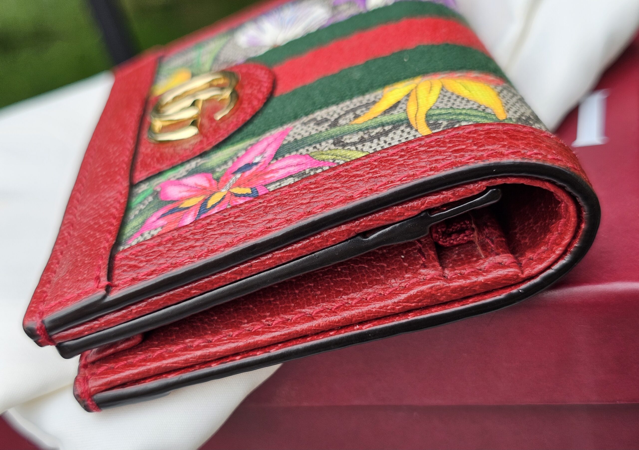 Side profile of the Gucci Flora Ophidia compact wallet showing the folded depth and red trim