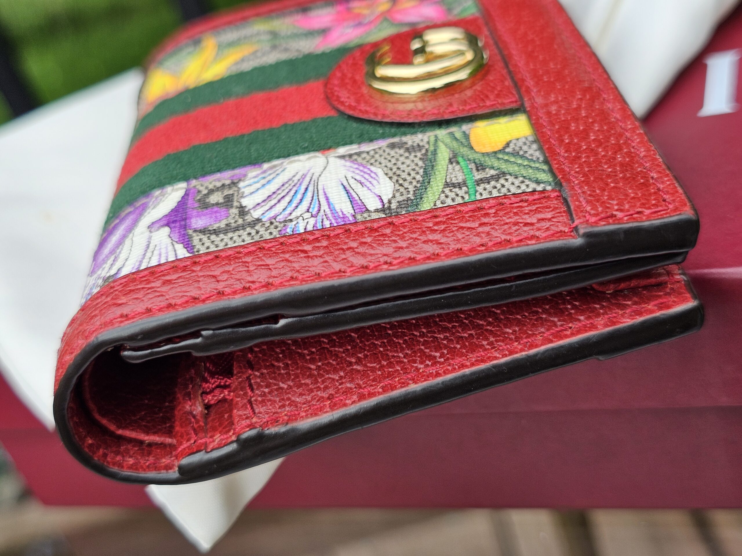 Angled view of the Gucci GG Supreme Flora Ophidia compact wallet with Double G closure
