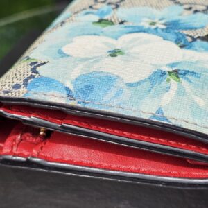 Gucci Blooms compact wallet showing the vibrant red leather interior against the blue floral canvas