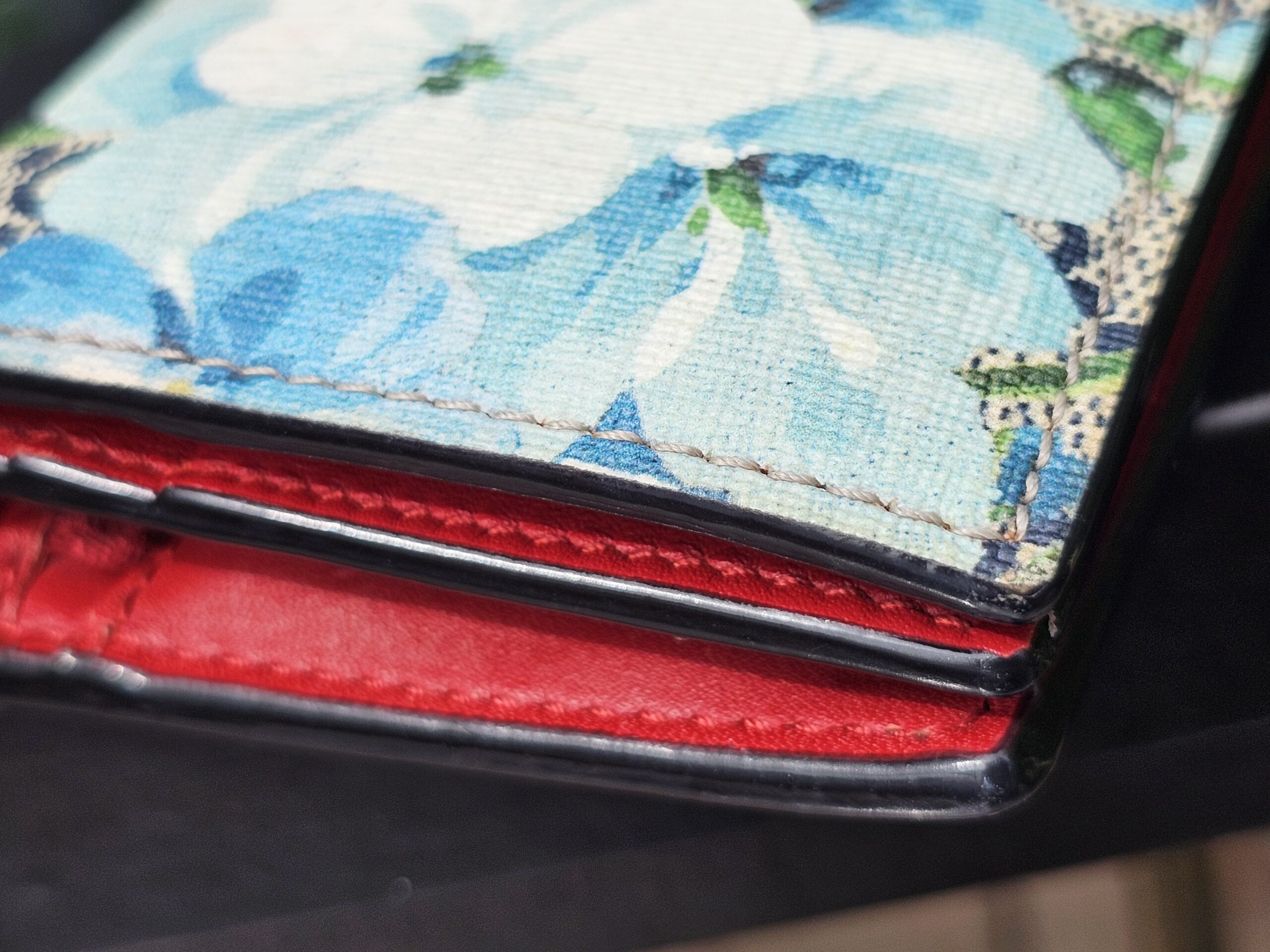 Edges of the Gucci Blooms compact wallet shown for minor rubbing from previous use