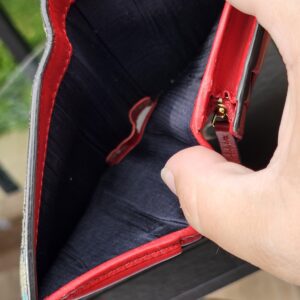 Gucci GG Supreme Blooms compact wallet held open showing the red leather and lined compartments