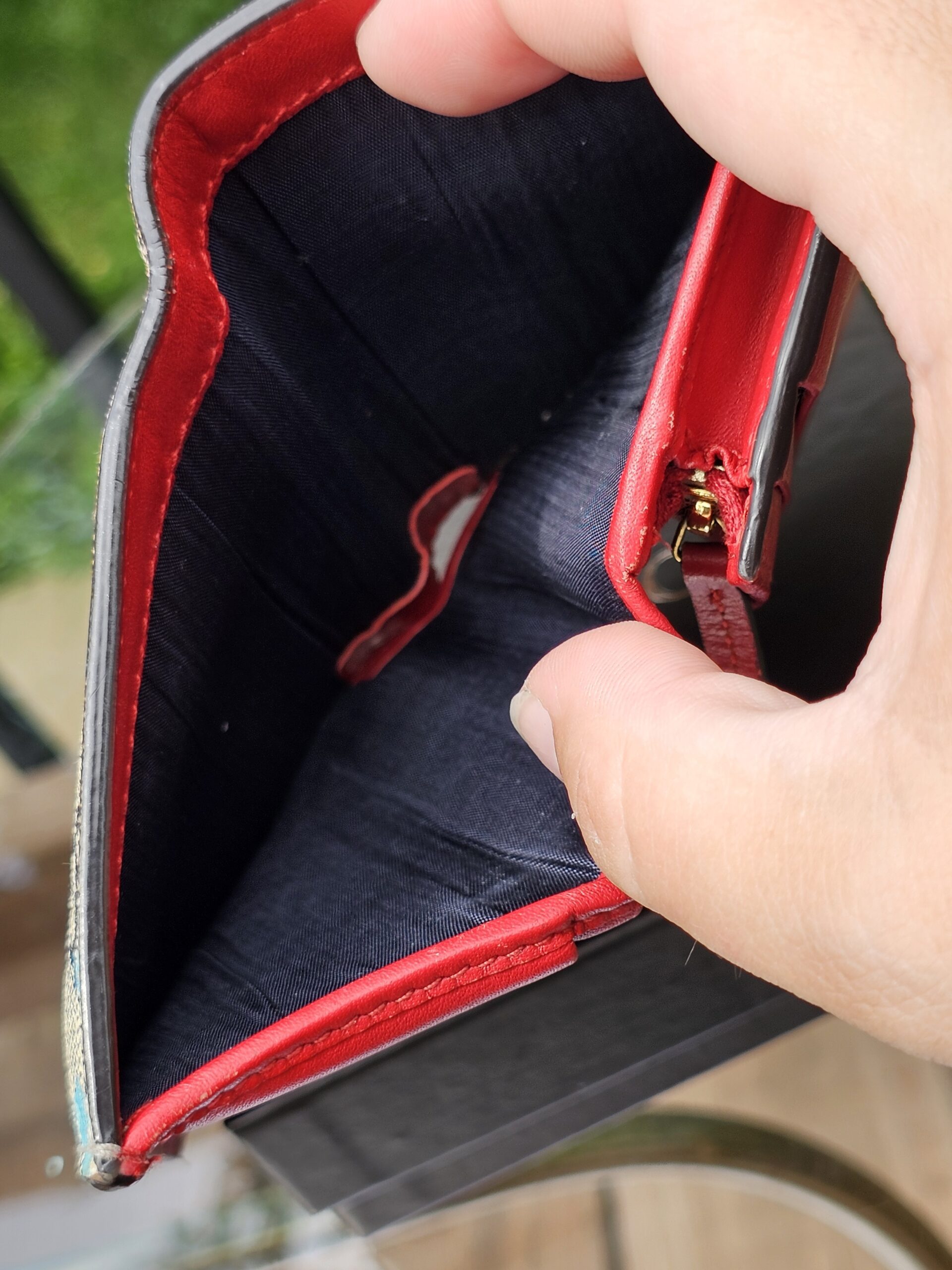 Gucci GG Supreme Blooms compact wallet held open showing the red leather and lined compartments