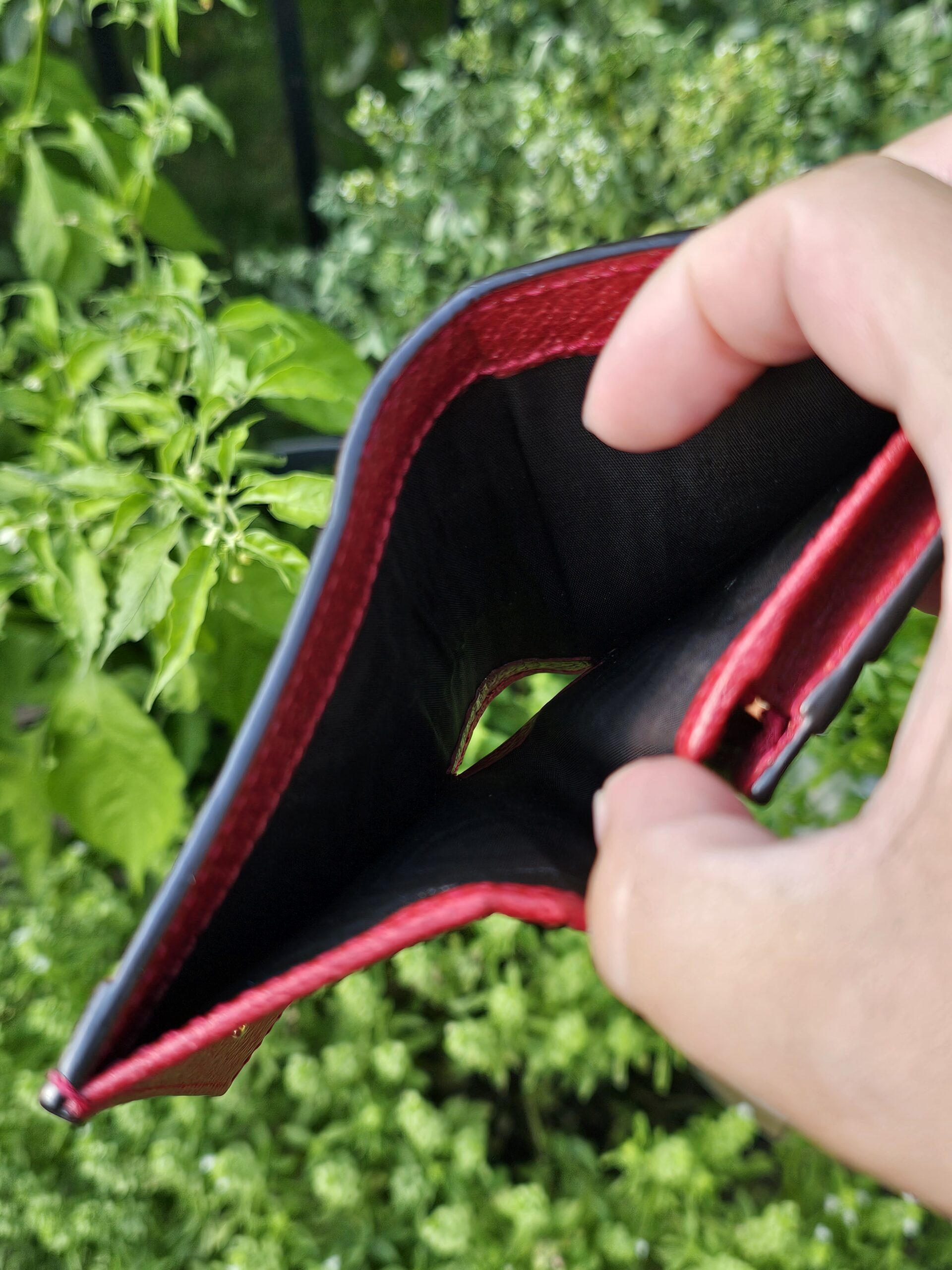 Gucci Flora Ophidia compact wallet held open showing the red leather and black lined coin compartment