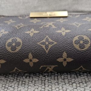 Top of the Louis Vuitton Favorite PM showing the gold-tone LV plate on the flap
