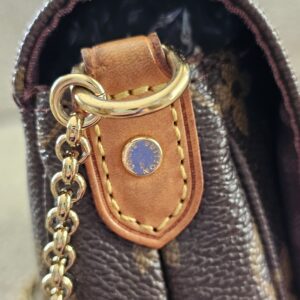 Gold-tone chain attached to the vachetta tab of the Louis Vuitton Favorite PM
