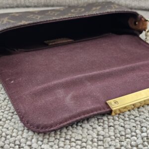 Louis Vuitton Favorite PM held open showing the burgundy lining and interior pocket