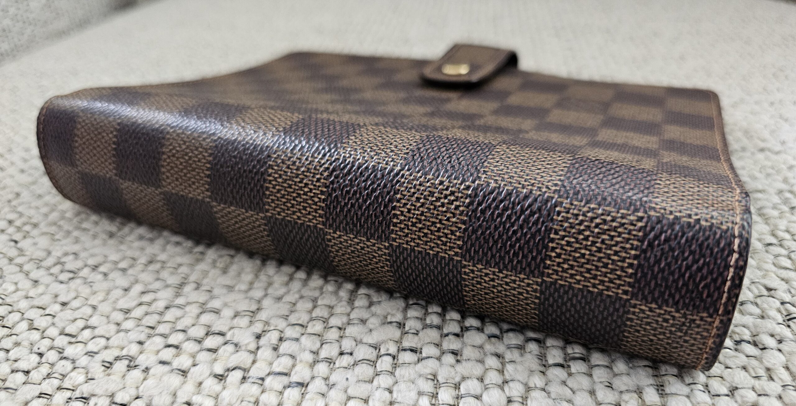 Side profile of the Louis Vuitton Medium Ring Agenda showing the snap tab