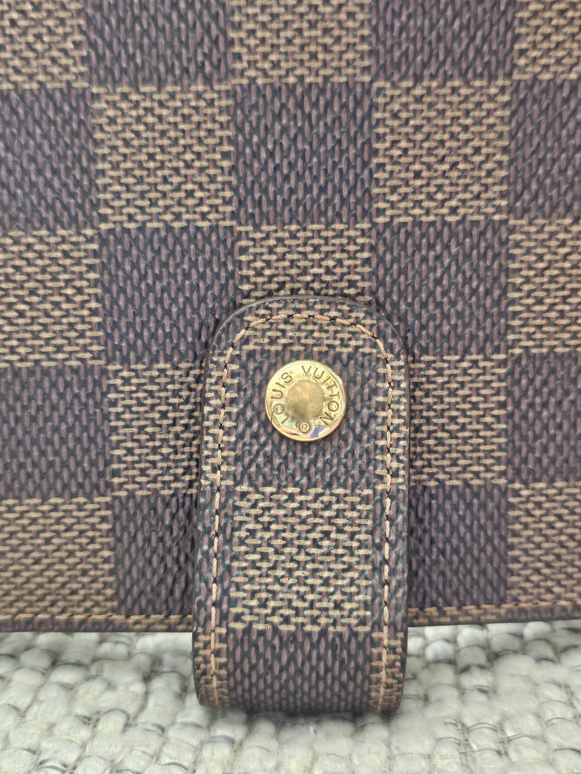 Gold-tone snap tab closure on the Louis Vuitton Damier Ebene Medium Ring Agenda