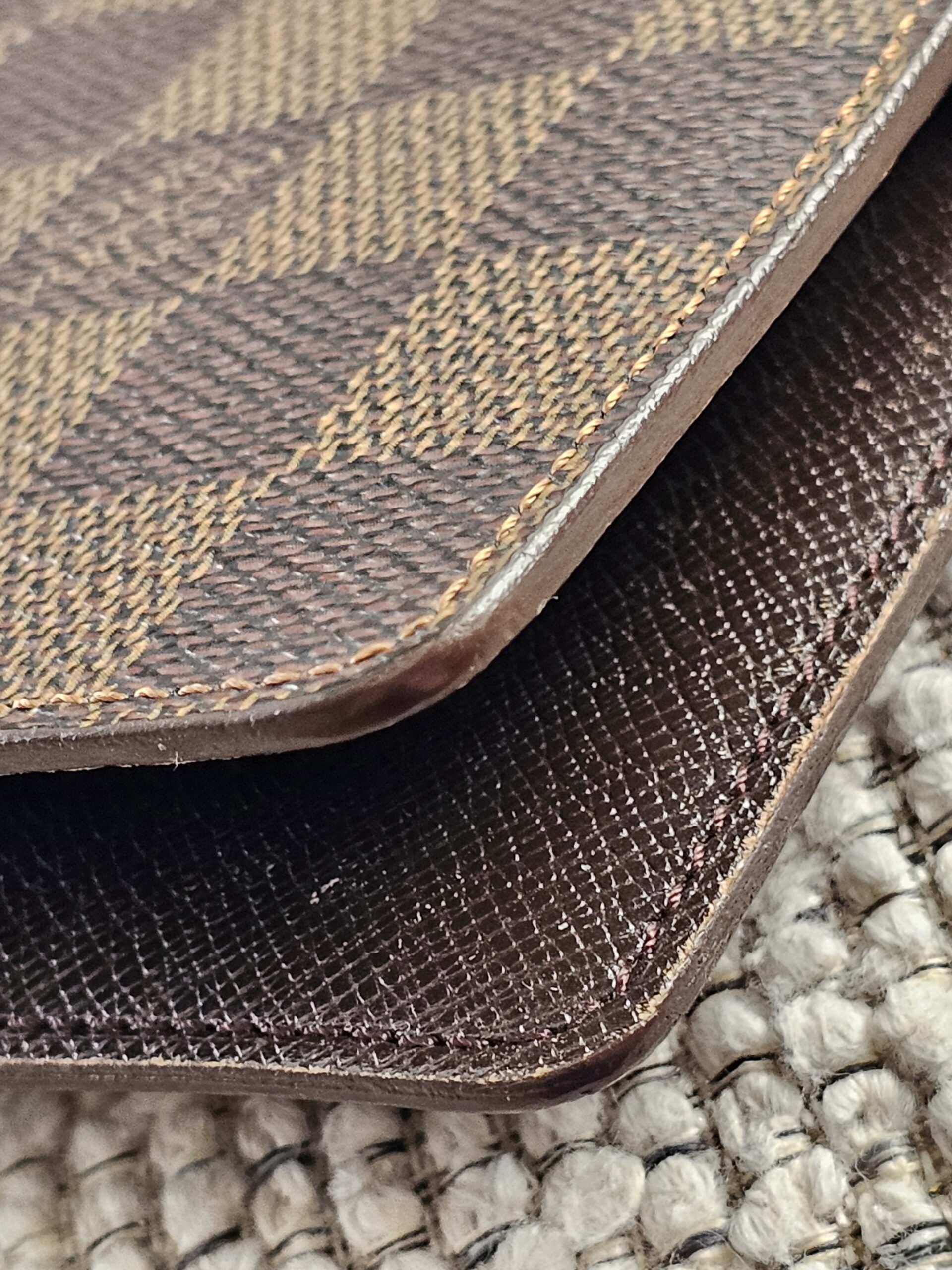 Edge of the Louis Vuitton Damier Ebene agenda shown for light wear from age