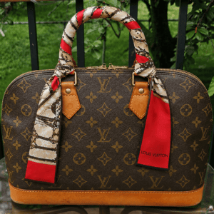 Louis Vuitton silk Trunks bandeau tied around the handle of a Monogram handbag
