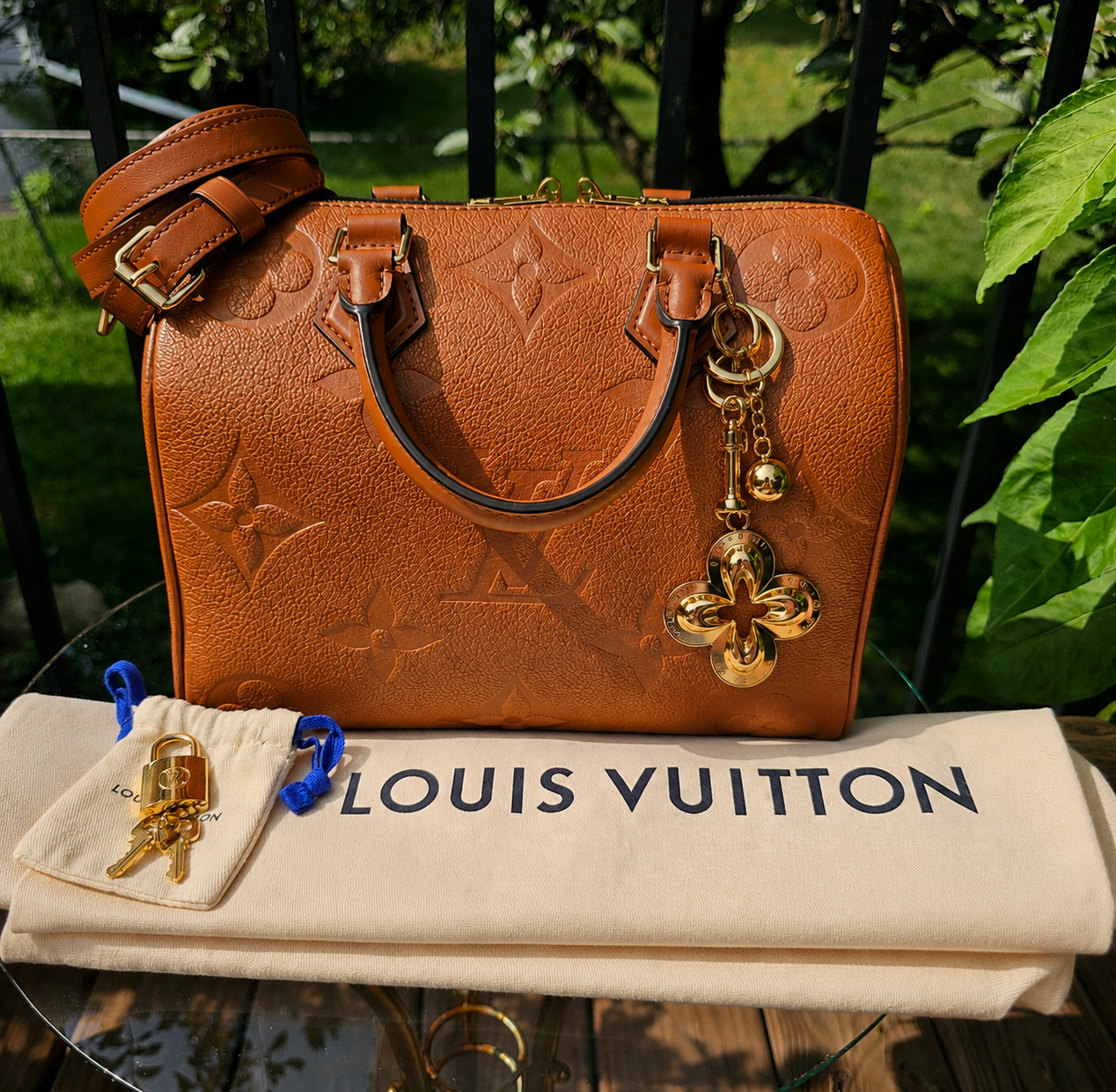 Louis Vuitton Eclipse gold-tone key holder and bag charm hanging from a leather handbag, shown for scale