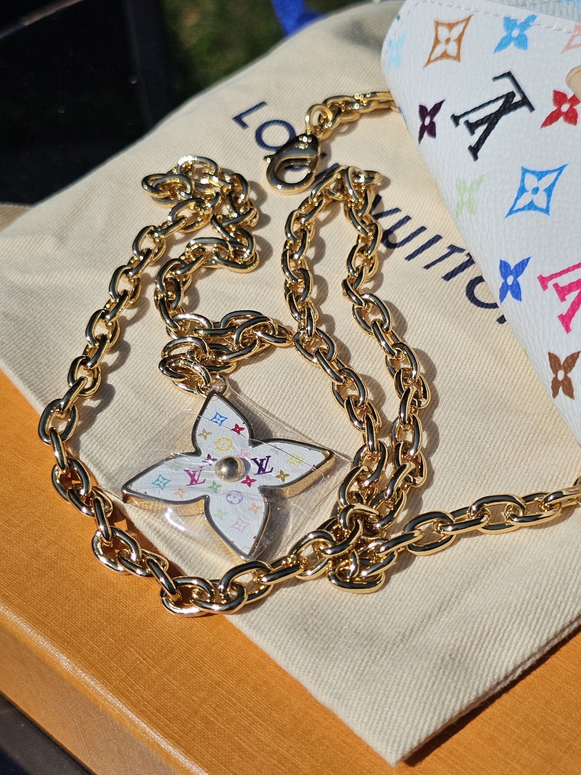 Gold-tone chain and Flowergram charm on the Louis Vuitton dust bag