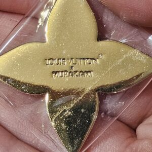 Reverse of the gold-tone Flowergram charm engraved LOUIS VUITTON MURAKAMI