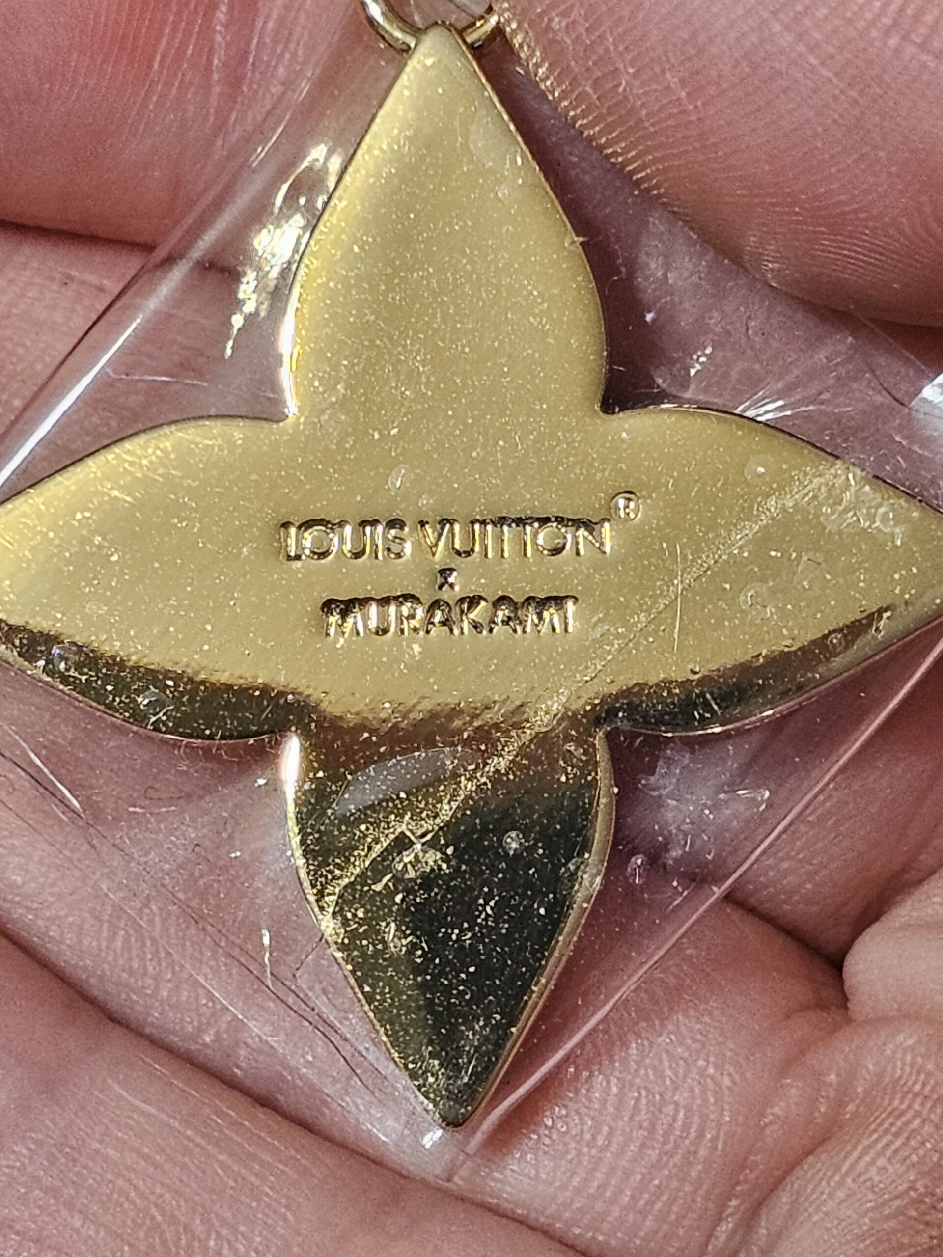 Reverse of the gold-tone Flowergram charm engraved LOUIS VUITTON MURAKAMI