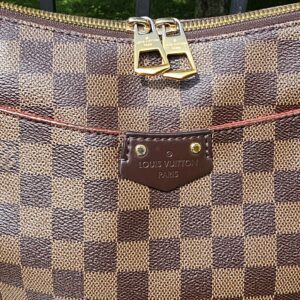 Double zip top closure of the Louis Vuitton South Bank Besace with red interior visible