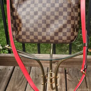 Louis Vuitton South Bank Besace hanging by its adjustable strap with the red underside showing