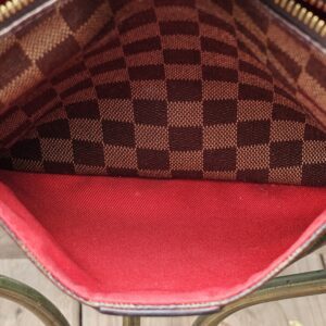 Louis Vuitton South Bank Besace held open showing the full red interior