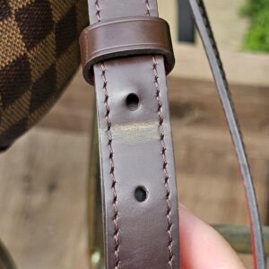Leather strap adjustment holes on the Louis Vuitton South Bank Besace showing minor wear