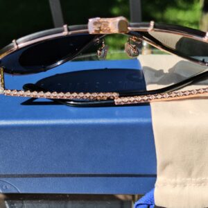 Angled view of the rose gold-tone LV Drive sunglasses with the temples folded, resting on the box
