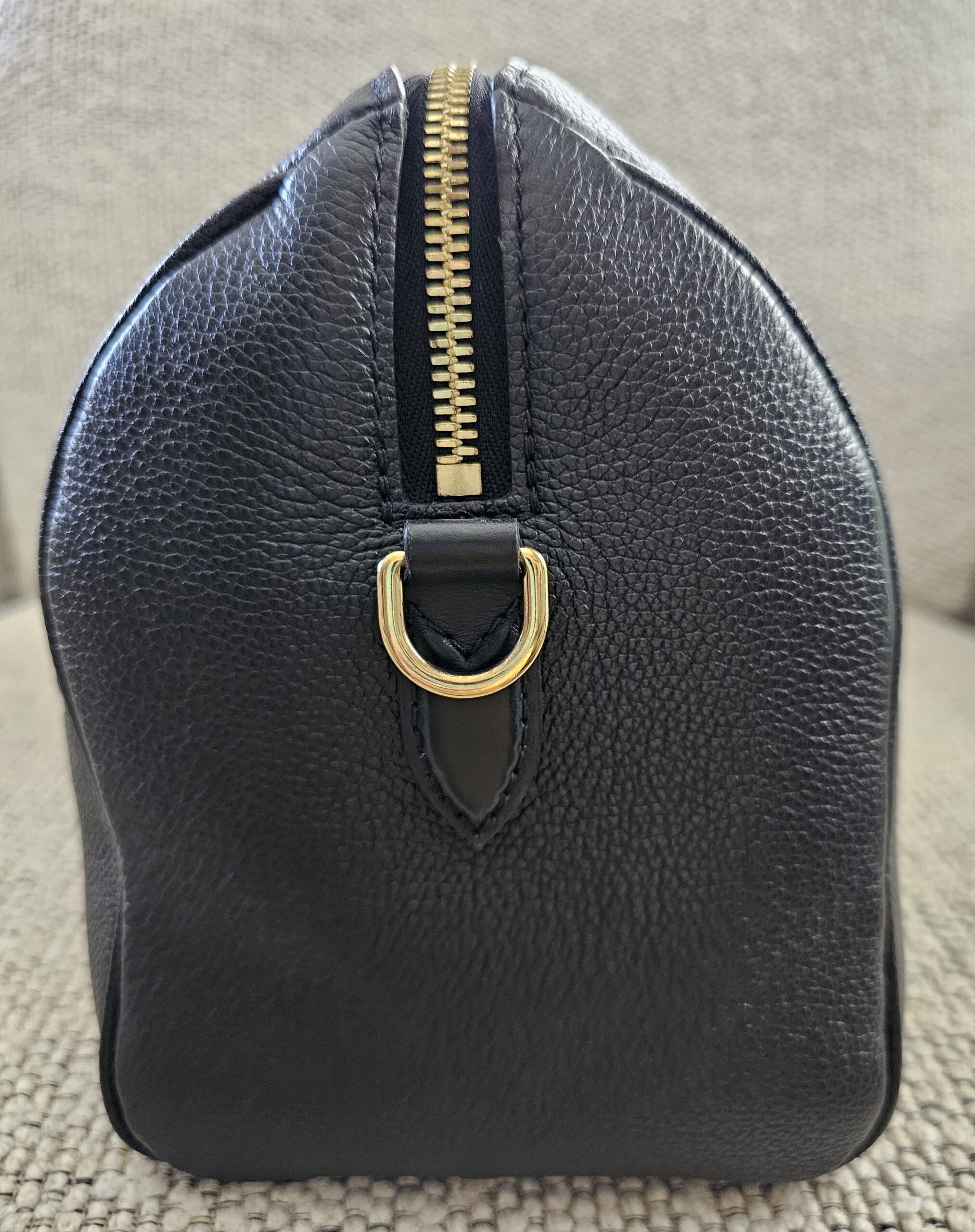 Side profile of the black Empreinte Speedy Bandouliere 25 with gold-tone D-ring