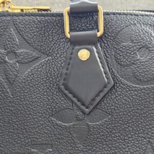 Leather tab and gold-tone stud on the black Giant Monogram Empreinte Speedy Bandouliere 25
