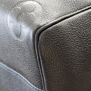 Bottom corner of the black Empreinte Speedy Bandouliere 25 with embossed monogram detail