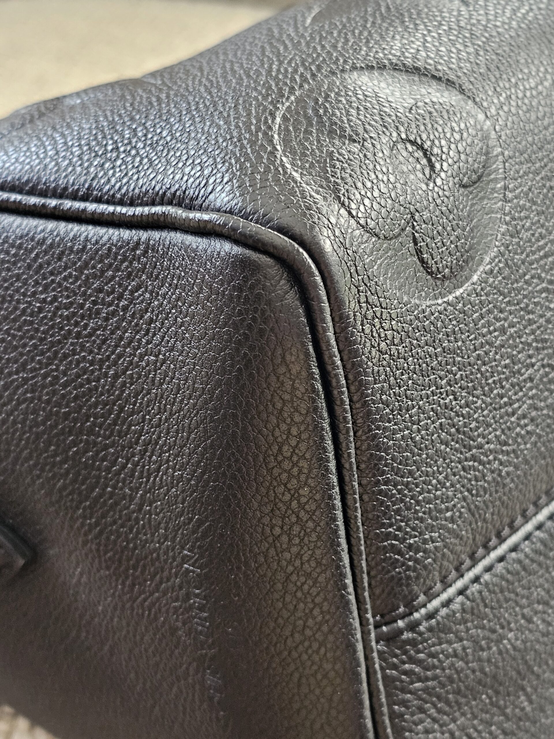 Embossed monogram flower at the corner of the black Empreinte Speedy Bandouliere 25