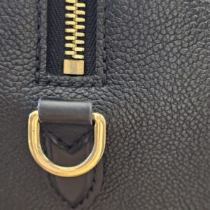 Zipper end and gold-tone D-ring on the black Empreinte Speedy Bandouliere 25