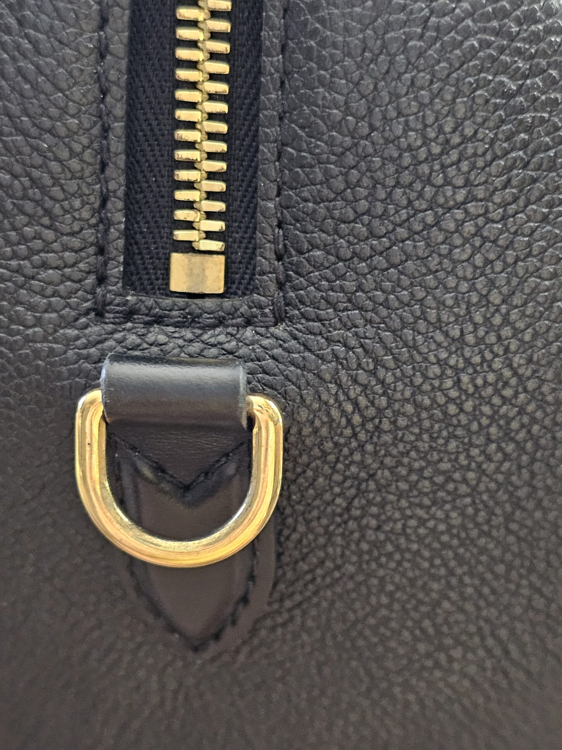 Zipper end and gold-tone D-ring on the black Empreinte Speedy Bandouliere 25