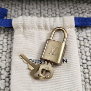 Louis Vuitton brass padlock and keys with their dust pouch, included with the Speedy Bandouliere 25
