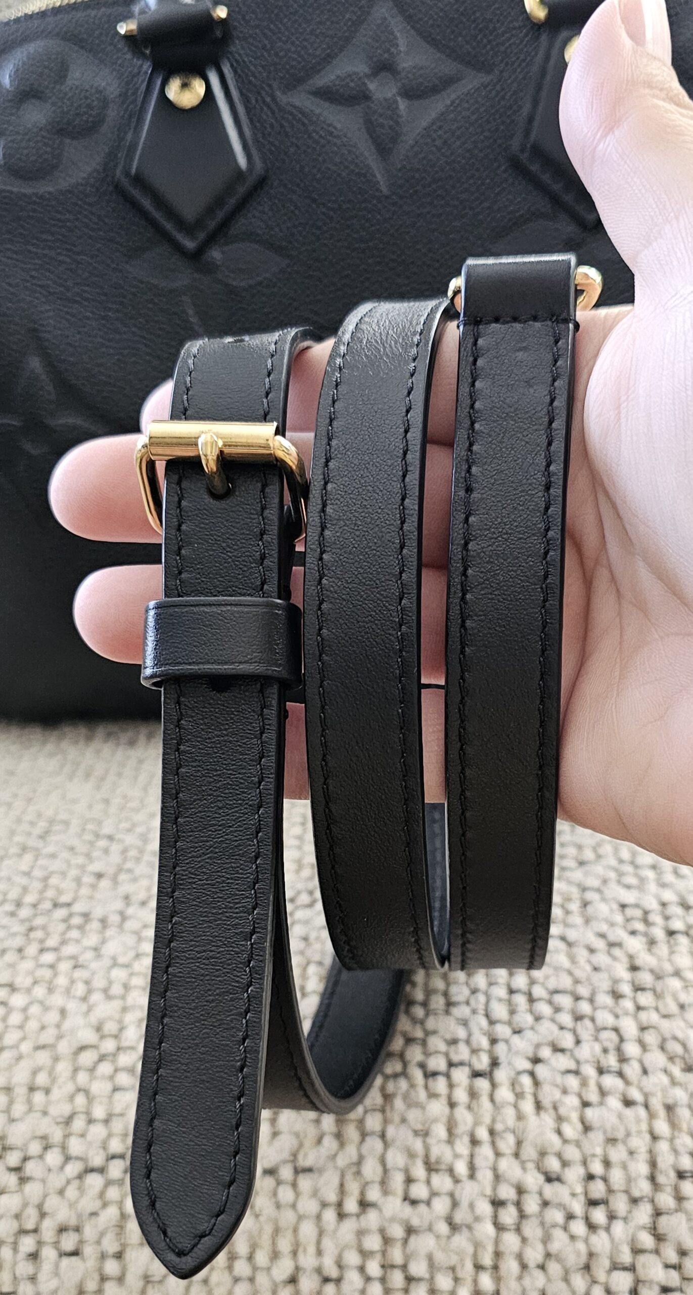 Adjustable black leather shoulder strap for the Empreinte Speedy Bandouliere 25 held in hand
