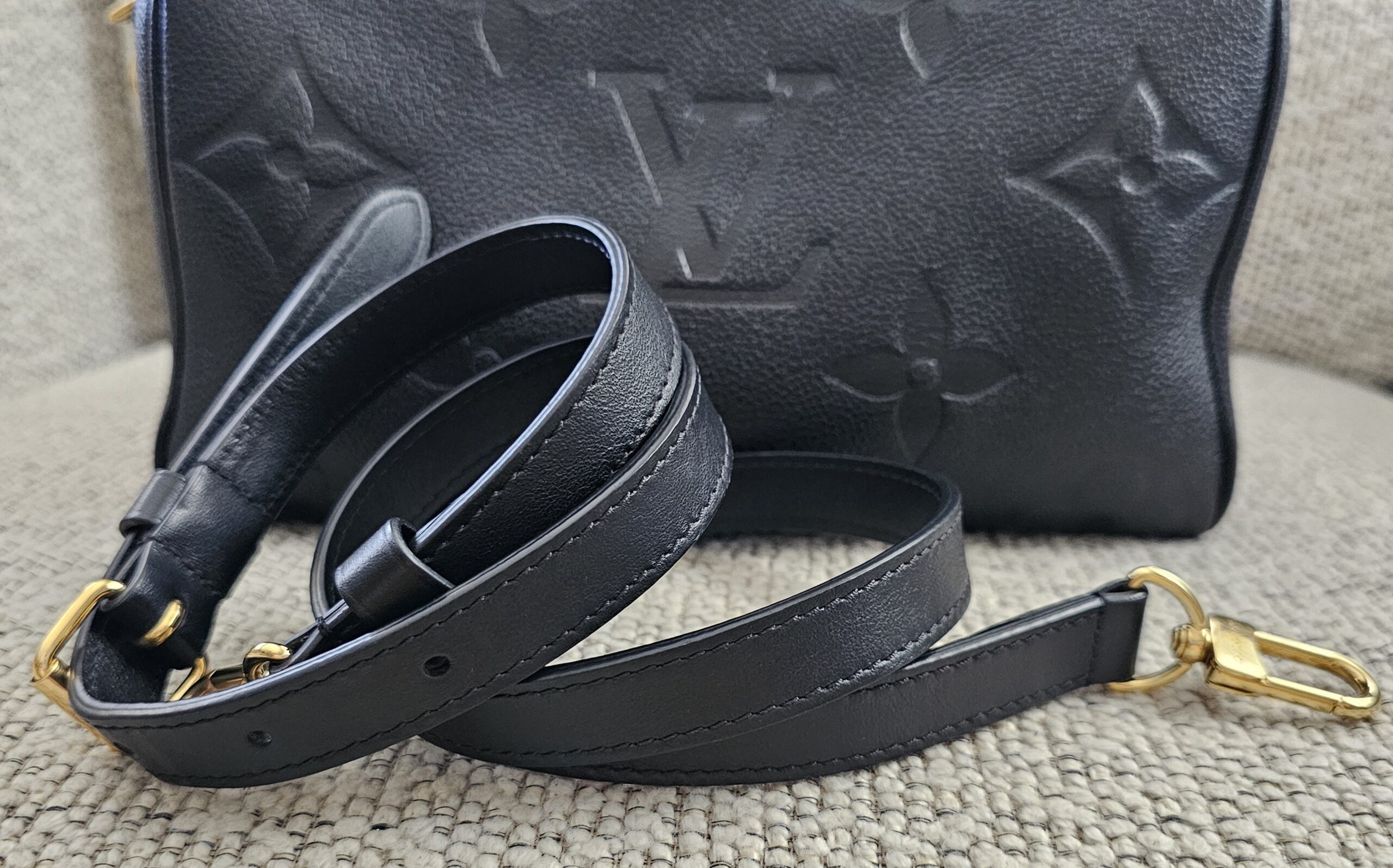 Black Empreinte Speedy Bandouliere 25 photographed with its leather shoulder strap coiled beside it