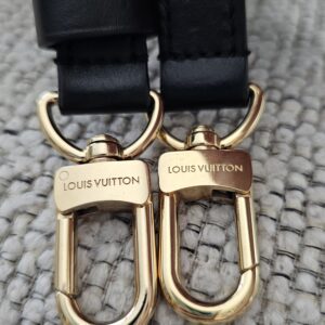 Engraved gold-tone snap hooks on the black leather shoulder strap of the Speedy Bandouliere 25