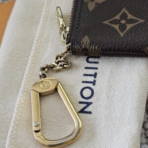 Gold-tone hook and chain on the Monogram Key Pouch resting on the dust bag