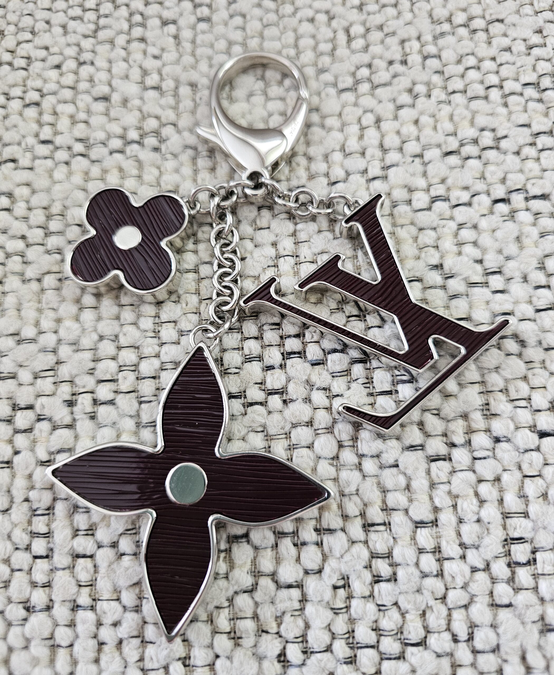 The LV initials, monogram flower and four-petal flower motifs of the plum Epi Fleur de Epi bag charm