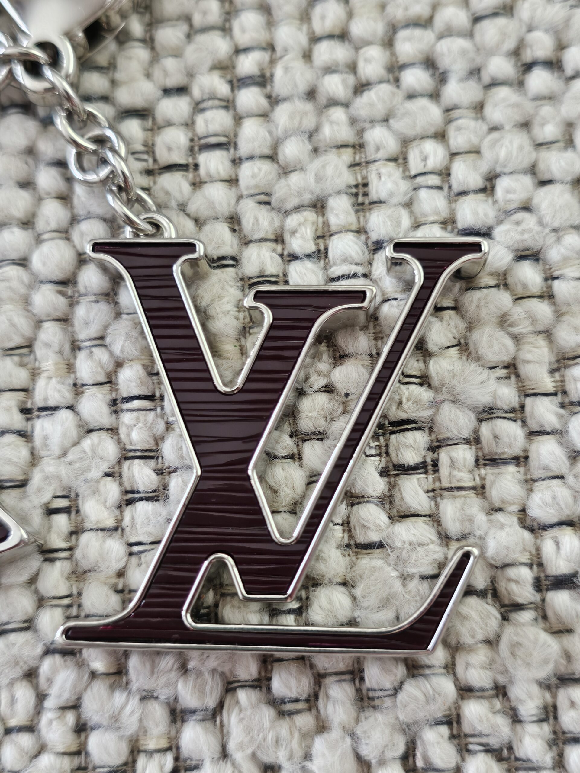 Close-up of the plum Epi LV initials motif on the Louis Vuitton Fleur de Epi bag charm