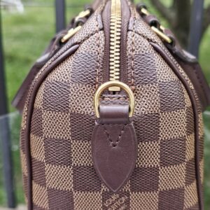 Side profile of the Damier Ebene Speedy Bandouliere 20 with gold-tone D-ring
