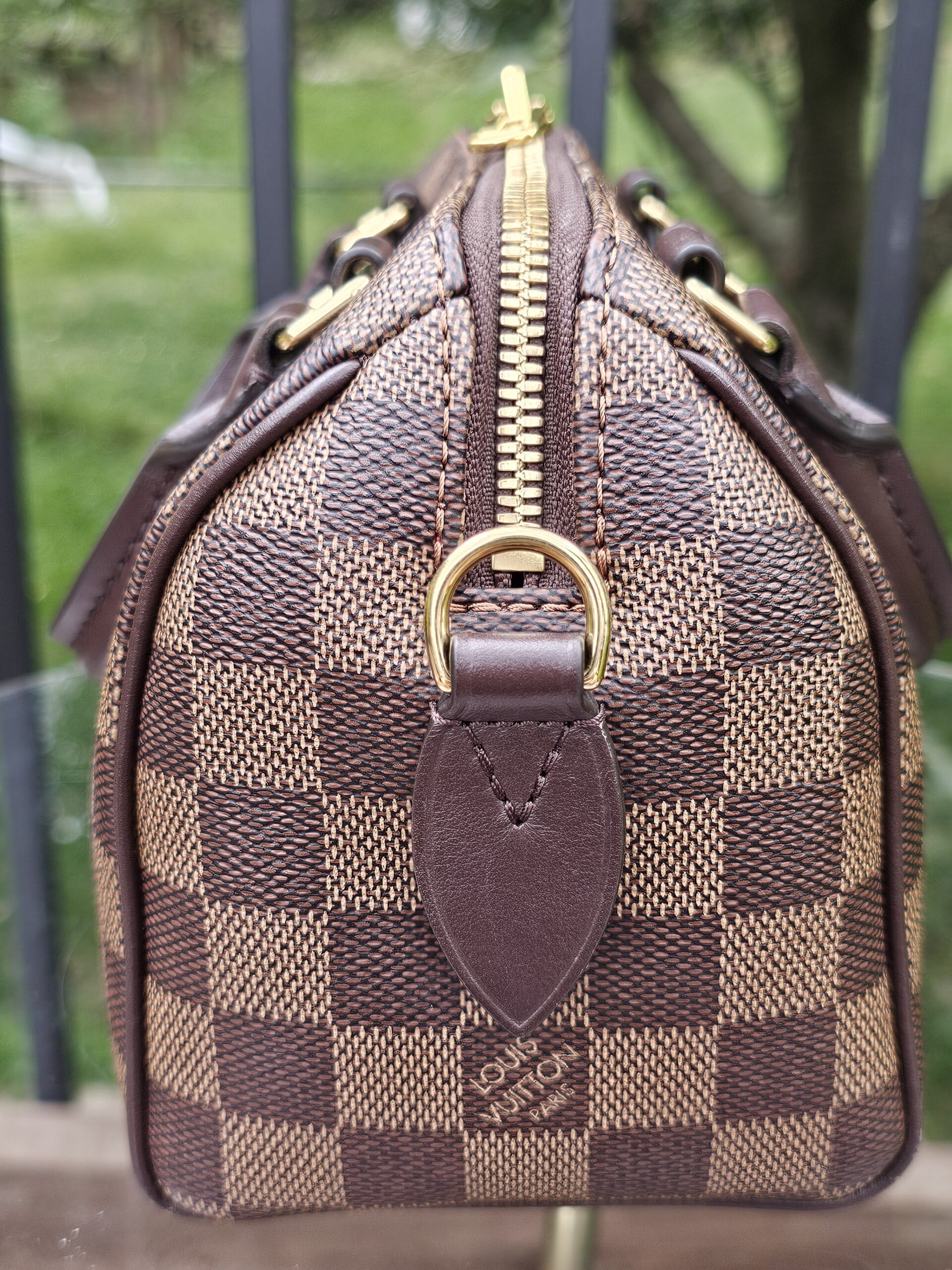 Side profile of the Damier Ebene Speedy Bandouliere 20 with gold-tone D-ring