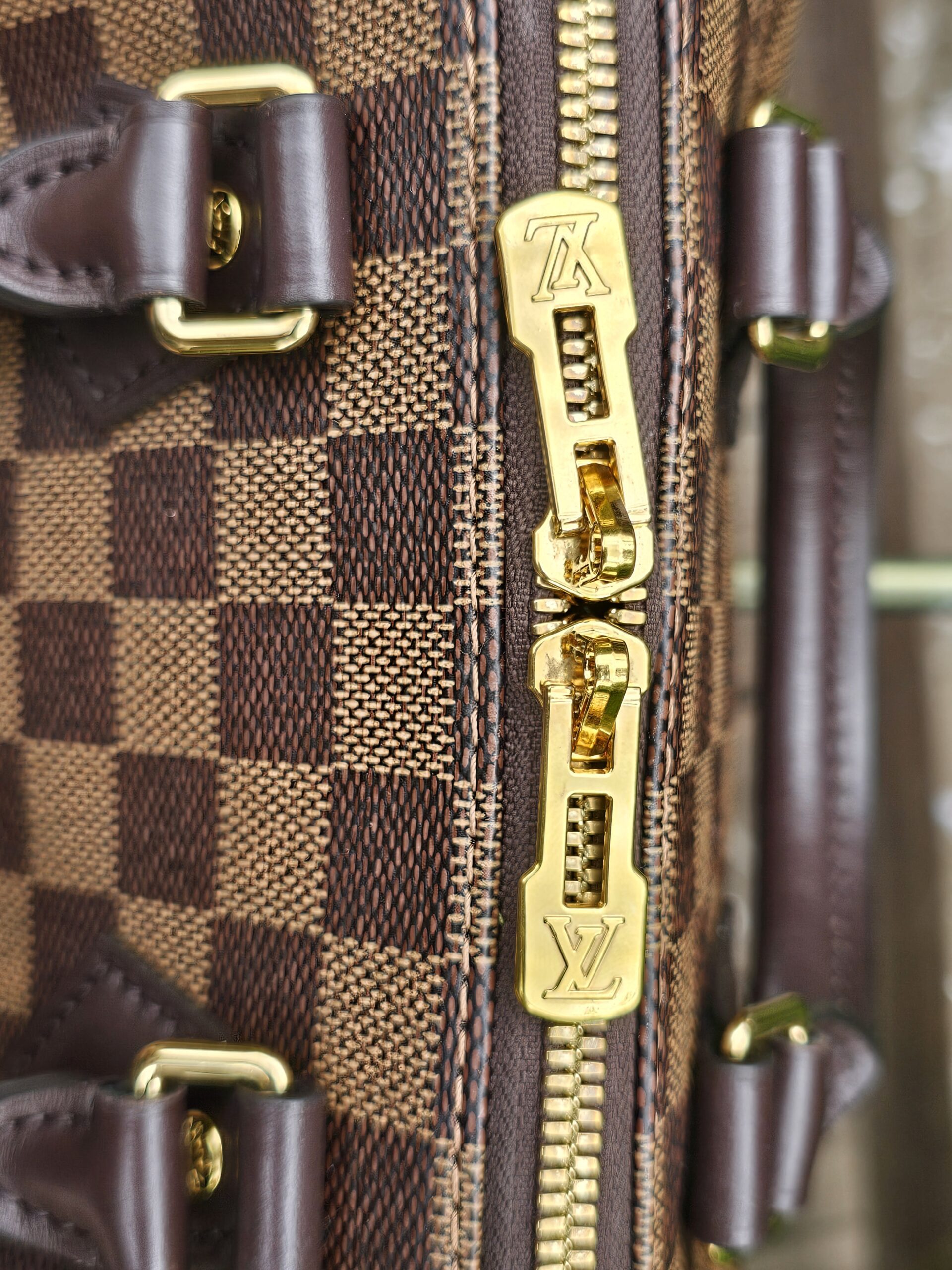 Close-up of the gold-tone zipper and pulls on the Damier Ebene Speedy Bandouliere 20