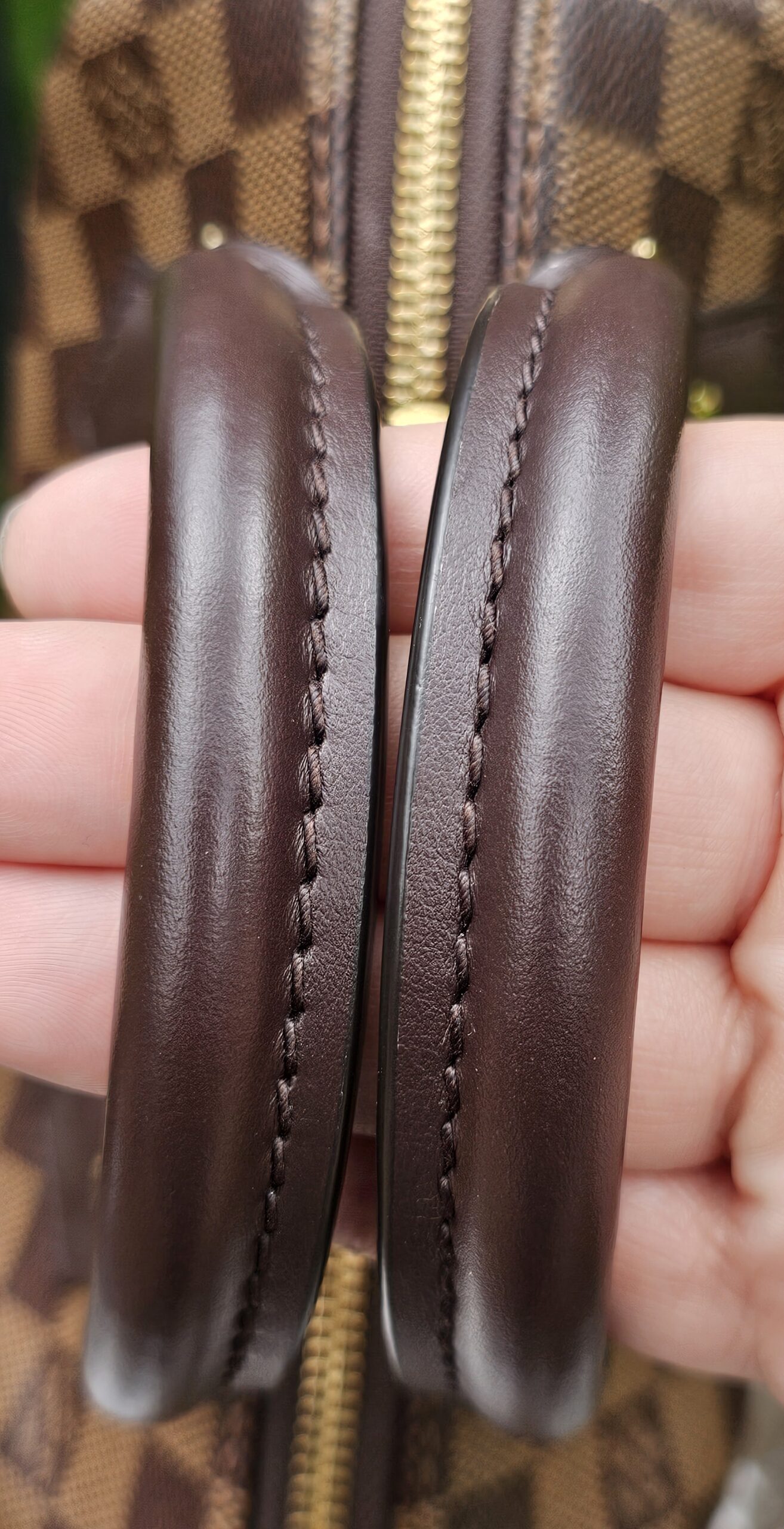 Rolled leather handles of the Speedy Bandouliere 20 held together to show their condition