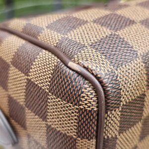 Close-up of a corner on the Damier Ebene Speedy Bandouliere 20 showing light wear