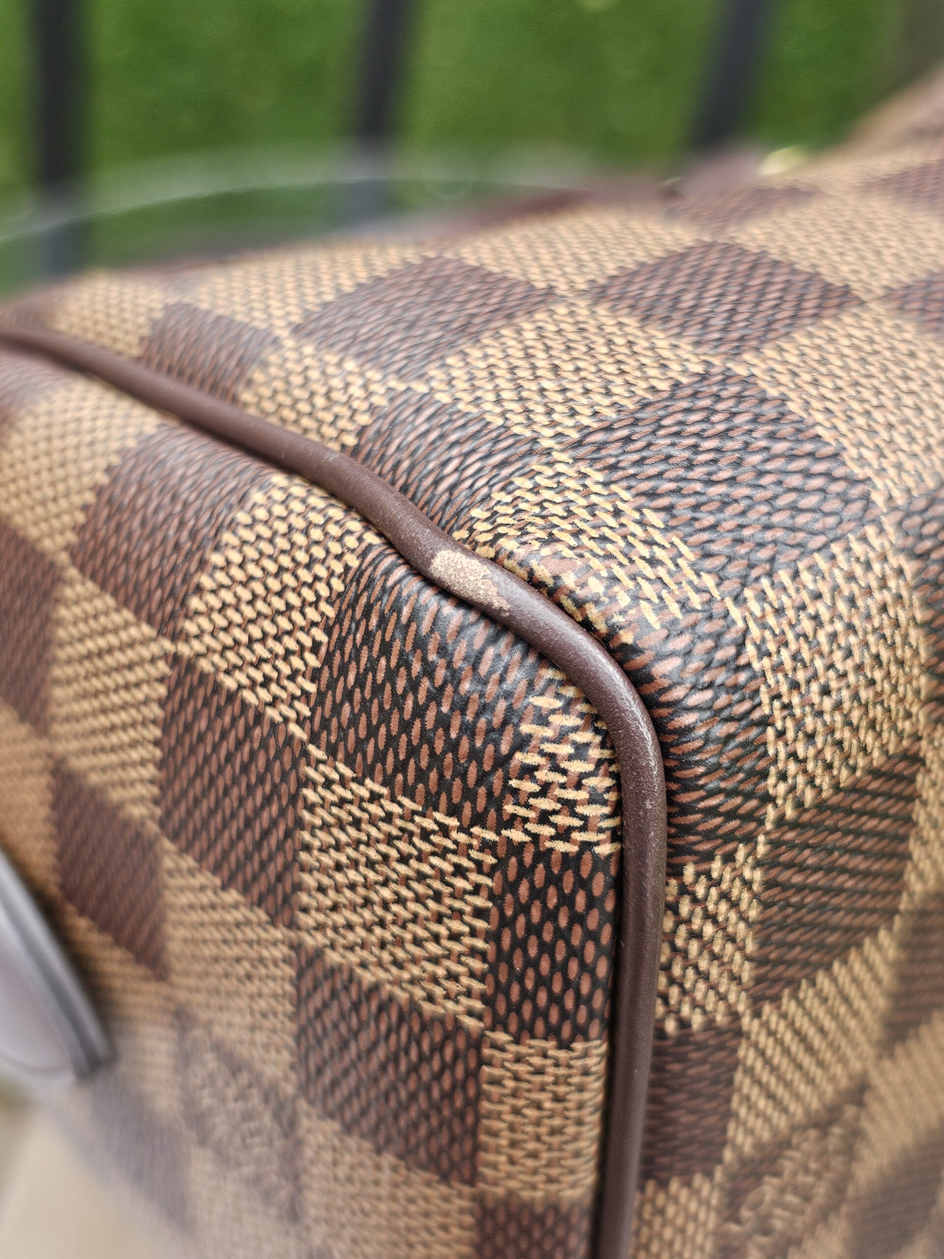 Close-up of a corner on the Damier Ebene Speedy Bandouliere 20 showing light wear