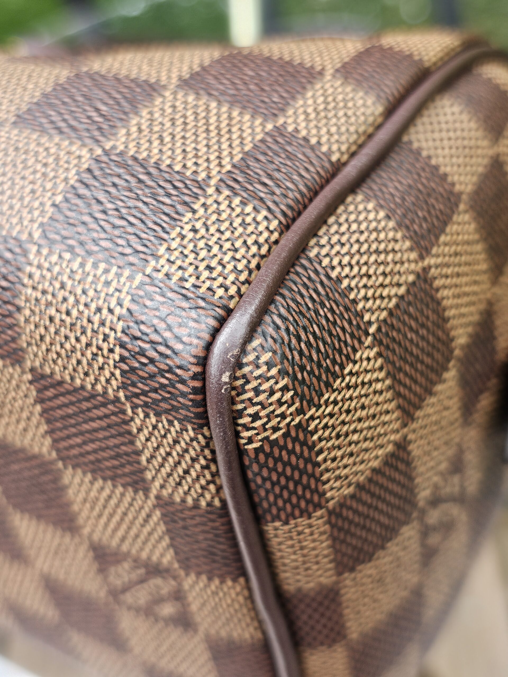 Close-up of the leather piping along the edge of the Damier Ebene Speedy Bandouliere 20