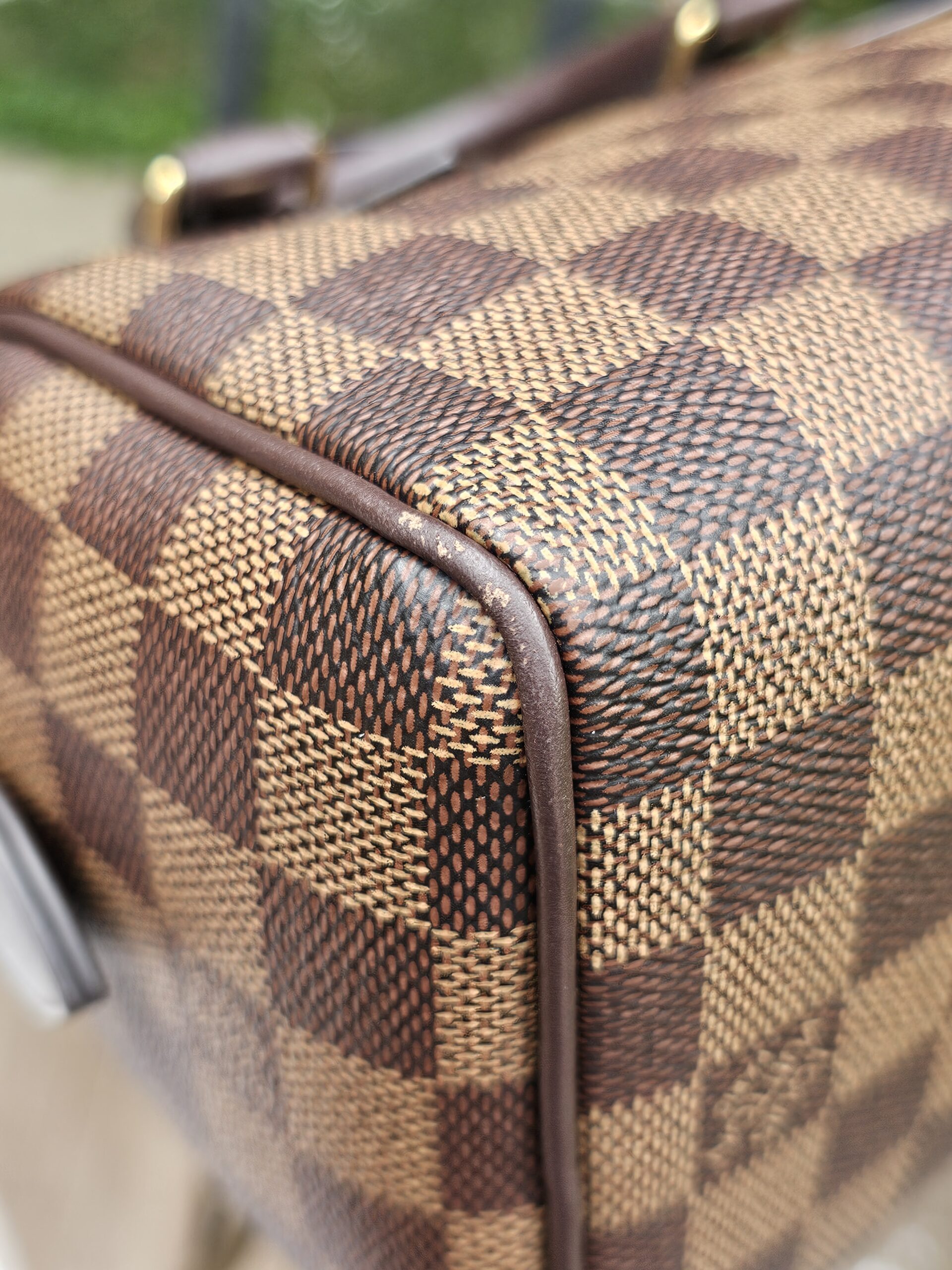 Top corner of the Damier Ebene Speedy Bandouliere 20 with canvas and trim in view