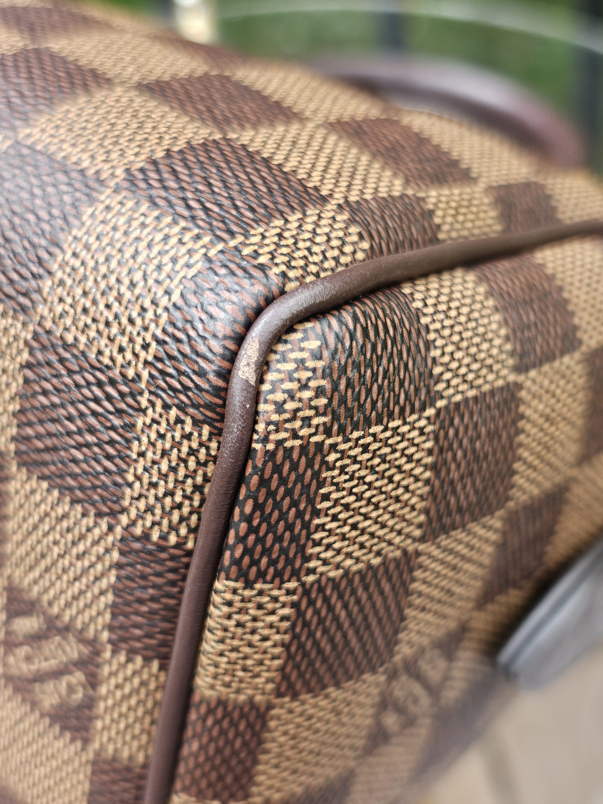 Side corner close-up of the Damier Ebene Speedy Bandouliere 20 canvas